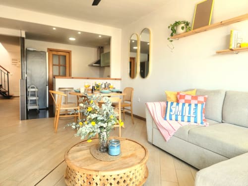 Moderno salón de BAKIT HOUSE en Águilas con sofá beige, mesa de madera, flores y vista abierta a la cocina