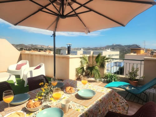 Terraza soleada en la azotea de BAKIT HOUSE en Águilas con zona de comedor, sombrilla, tumbonas y vistas a las montañas