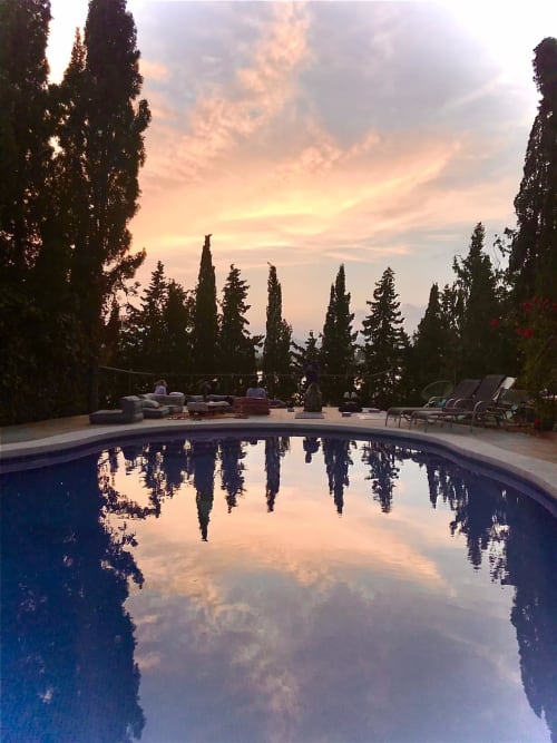 Reflejo del atardecer en la piscina de la villa Bakit House en Águilas con cipreses