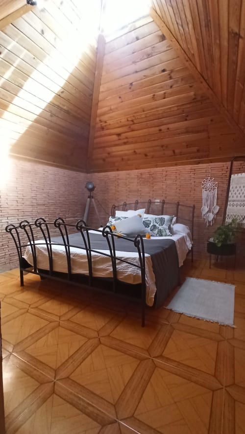 Amplio dormitorio en la villa Bakit House, Águilas, con cama de hierro forjado, techos de vigas de madera y paredes de ladrillo