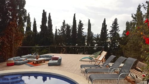Terraza con piscina de la villa Bakit House en Águilas con tumbonas, asientos y cipreses