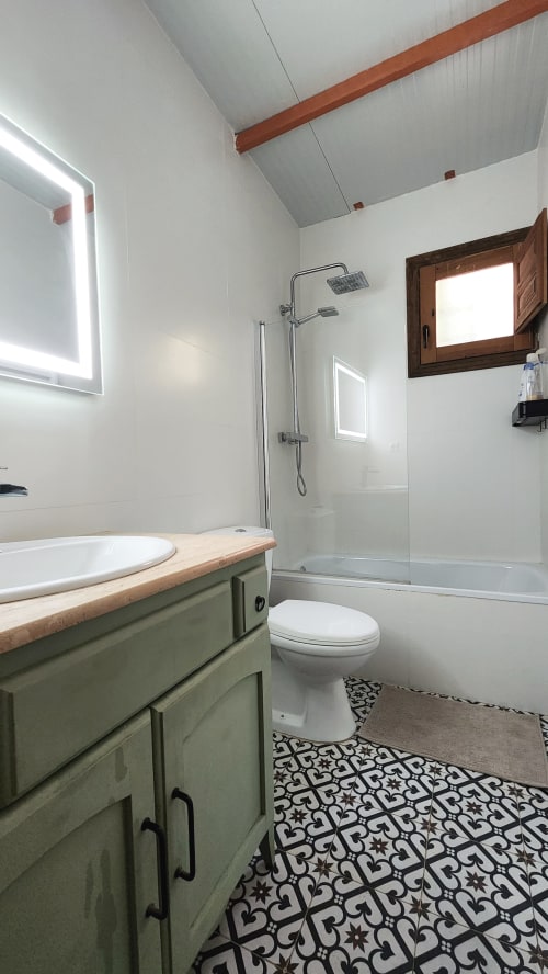 Baño moderno de la villa Bakit House en Águilas con tocador verde, mampara de ducha cristal y baldosas con patrón