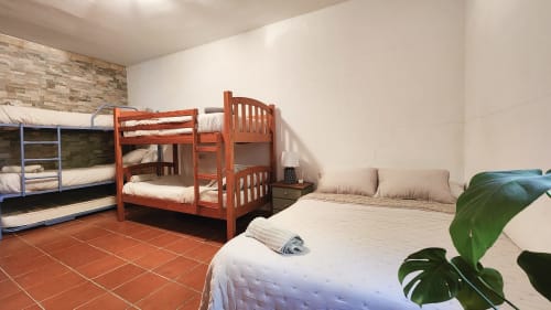 Espacioso dormitorio de villa en Bakit House en Águilas con literas de madera, cama individual, suelo de barro y decoración con plantas