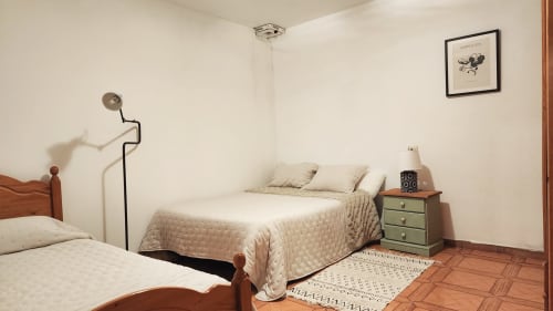 Dormitorio luminoso en villa Bakit House en Águilas con dos camas, mesilla verde, lámpara de pie metálica y cuadro en pared blanca