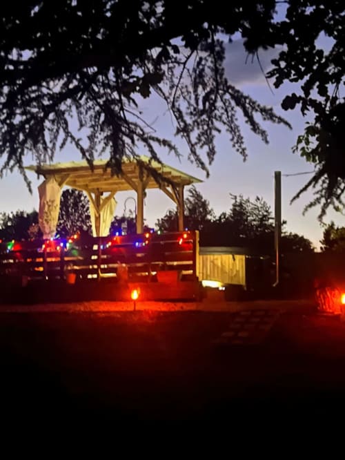 Twilight ambiance at Domaine le Manoir with illuminated wooden gazebo and colorful fairy lights in Fossemagne