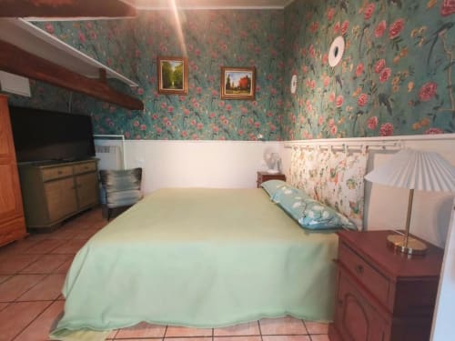 Chambre pastel au B&B Le Coin des Artistes avec papier peint fleuri, lit queen, TV et décoration française classique