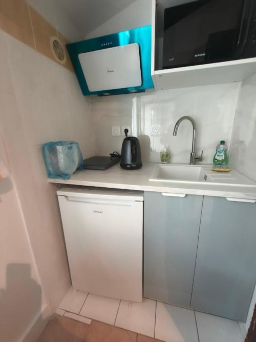 Kitchenette compacte dans la chambre Pastel du gîte Le Coin des Artistes avec évier, réfrigérateur, bouilloire et hotte turquoise