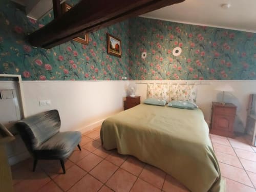 Chambre pastel à Le Coin des Artistes avec papier peint fleuri, literie jaune et carrelage en terre cuite