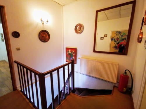 Escalier de la chambres d'hôtes Le Coin des Artistes avec assiettes décoratives, miroir, radiateur et extincteur rouge