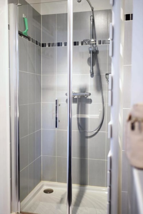 Salle de bain moderne avec carrelage gris et douchette pluie à Le Coin des Artistes B&B en France