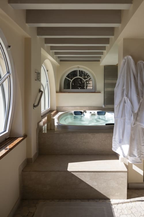 Lussuoso bagno spa della villa I Wish Italy con vasca idromassaggio riscaldata, finestra ad arco, scaldarottoli riscaldati e pavimento in marmo