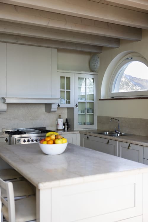 Cucina moderna con cabinetry bianca, piano in marmo e finestra ad arco con vista sul Lago di Como a Le Selve villa, Toscolano