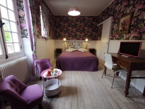 Chambre Nymphéas au Coin des Artistes B&B en France avec fauteuil en velours mauve, papier peint fleuri et lit aux draps mauves