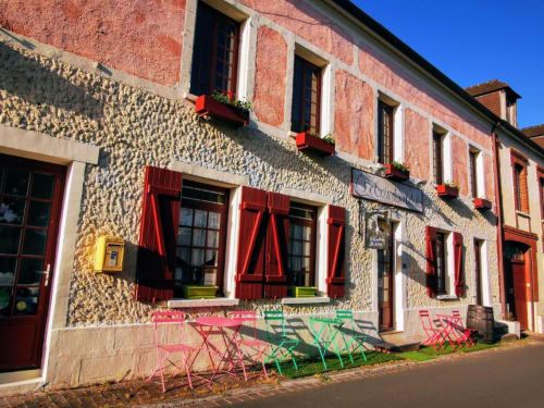 Extérieur du charmant gîte Le Coin des Artistes avec volets rouges, terrasse café colorée et façade en pierre rustique