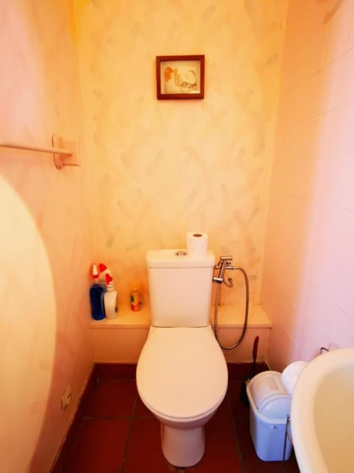 Salle de bains immaculée aux fixtures blanches en porcelaine, murs crème et cadres d'art décoratifs au Coin des Artistes