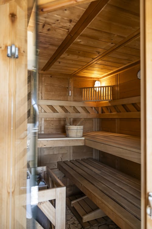 Sauna in legno presso Le Selve Hilltop Pool Villa a Toscolano Maderno con panche a gradini e pietre riscaldate
