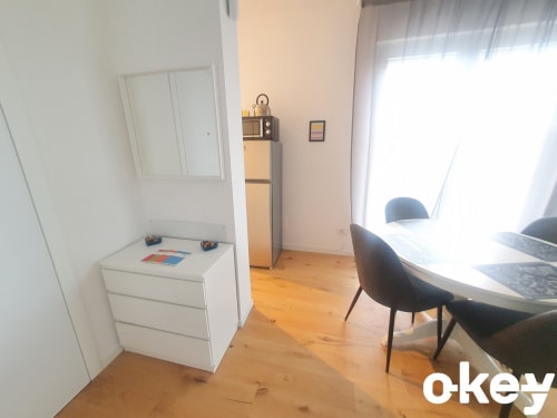 Camera da letto moderna in appartamento sulla spiaggia di Bari con comò bianco, scrivania, sedia nera, pavimento in legno e finestre luminose