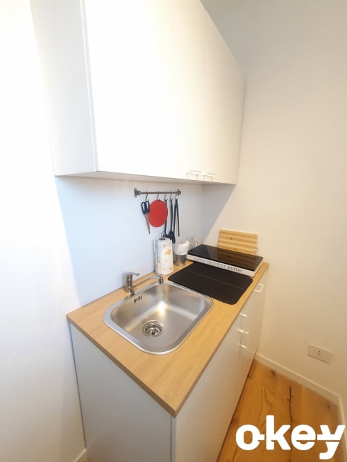 Piccola cucina in appartamento fronte mare a Bari con lavello in acciaio inox, piano di lavoro in legno e utensili da cucina a parete