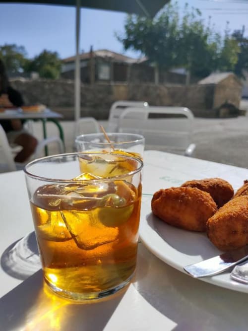 Iced beverage and fried appetizers on white table at Posada de Ollo, Spain
