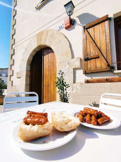 Sausages and pastries served on white plates at Posada de Ollo terrace with rustic stone architecture in Ollo, Spain