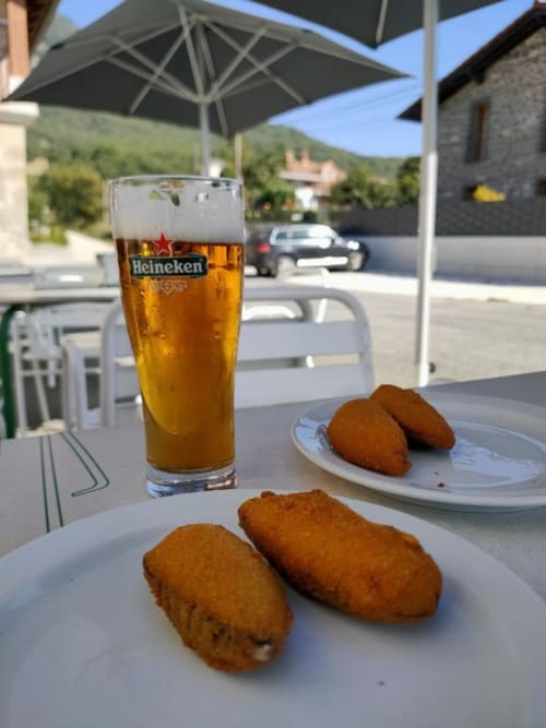 Heineken beer and fried croquetas served at Posada de Ollo terrace with mountain views in Ollo, Spain