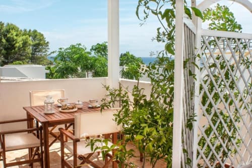 Terrazza soleggiata di Santa Cesarea Vacanze con tavolo da pranzo in legno, vista sul mare e rampicanti, Italia