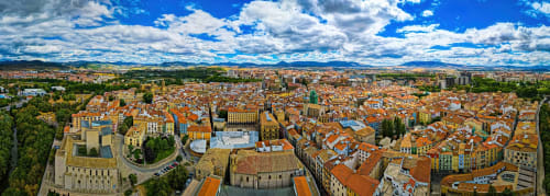 Aerial view of Ollo townscape with red-roofed buildings, historic architecture, and surrounding landscape under blue sky