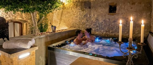 Couple relaxing in candlelit hot tub at Le Clos Des Anges luxury B&B in Bagnols, France