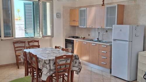 Cucina e zona pranzo luminosa di Santa Cesarea Vacanze con tavolo in legno, elettrodomestici e finestre con vista sul mare