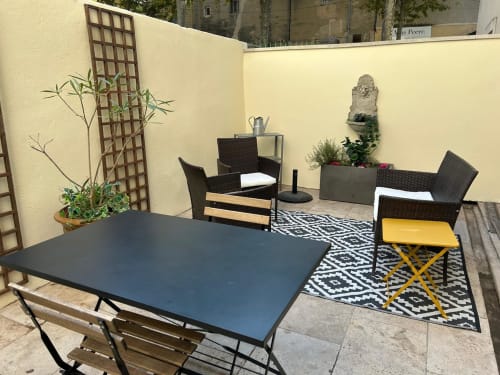 Terrasse extérieure de la Conciergerie Maurin à Arles avec table de salle à manger, chaises en rotin et plantes en pots