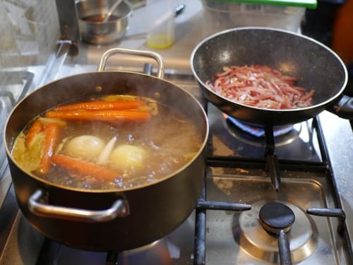 Deux casseroles sur la cuisinière de la Bresbot B&B : un bouillon avec légumes et pommes de terre, viande hachée qui cuit dans un wok