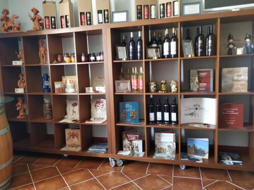 Wooden shelving display with wine bottles, books, and decorative items at RISOTURISMO Portuguese heritage property