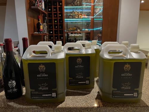 Large olive oil jugs from Solar de São João displayed on counter in Portuguese wine tasting room with wine bottles and