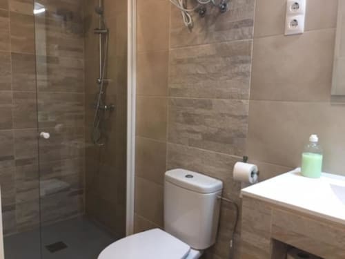 Modern bathroom at Hotel Skyline with glass shower, white toilet, and marble tiled walls in Alcorcón