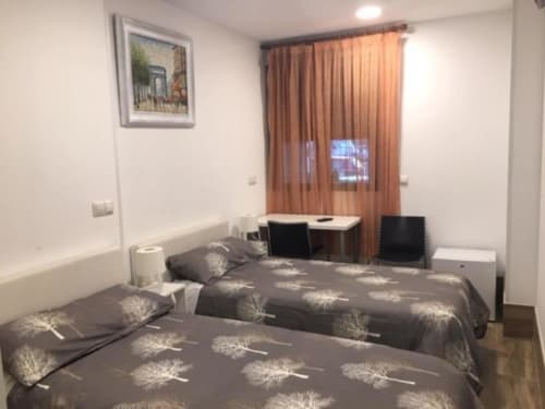 Modern hotel room at H Skyline in Alcorcón with two beds, work desk, orange curtains and minimalist décor