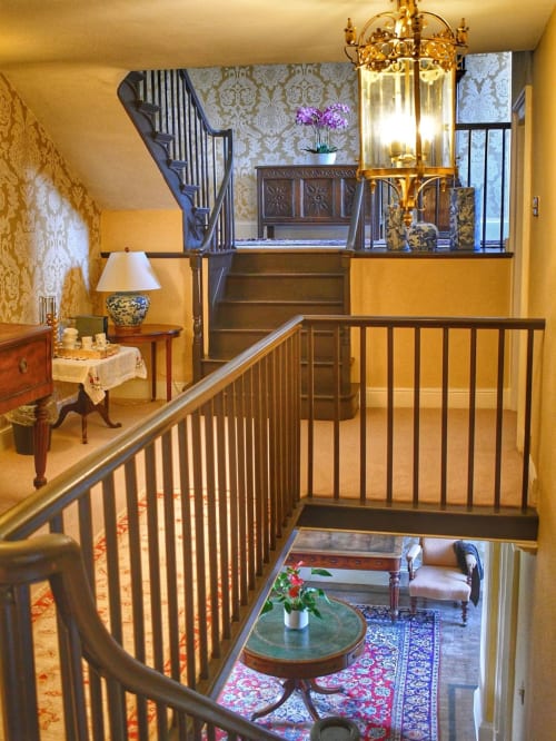 Elegante Treppenabsatz in der Florence Nightingale Suites in Derbyshire mit Damasttapete, Messingkronleuchter und Stilmöbeln