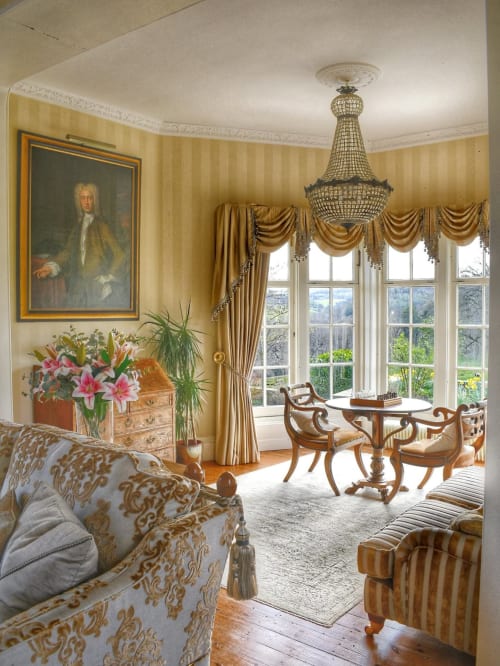 Elegantes Wohnzimmer in den Florence Nightingale Suites, Holloway mit goldgestreiften Wänden, antikem Mobiliar, Kronleuchter und Erker