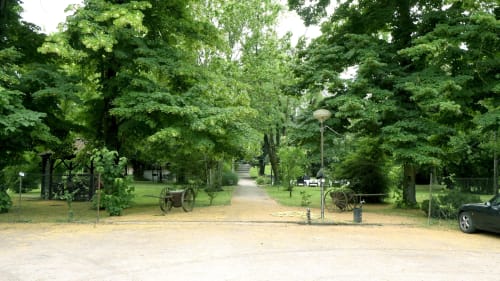 Ingresso del Bresbot B&B a Bressana con viale alberato, carri rustici e giardini rigogliosi