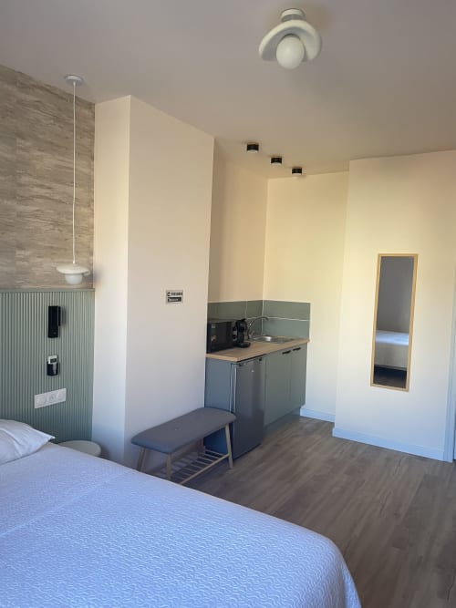 Chambre à l'Hôtel Les Paquebots avec lit, kitchenette, douche et mobilier moderne à Port-Vendres