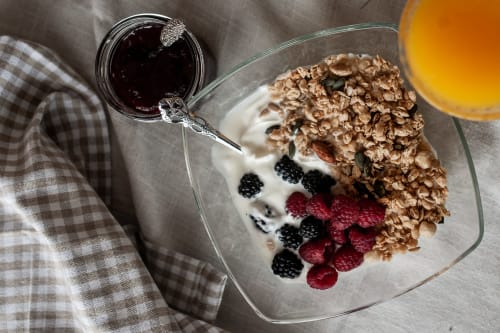 Tigela de pequeno-almoço na Herdade da Cova da Onça com granola, iogurte, frutos silvestres, compota e sumo