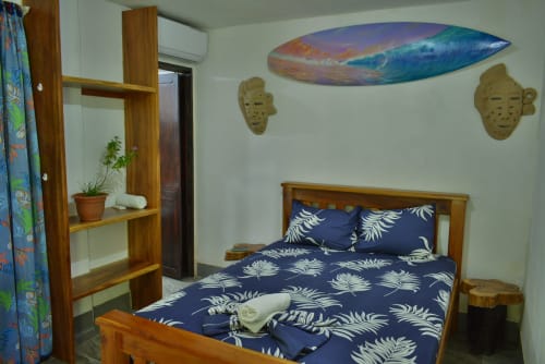 Acogedora habitación del Hotel Swell Pavones en Pavones con cama de madera, ropa de cama con estampado de palmeras azules y decoración costera