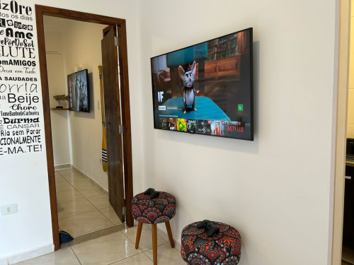 Sala de estar moderna no apartamento BORA BORA HOSPEDAGENS em Joinville com TV de 50 polegadas, pufes decorativos e entrada