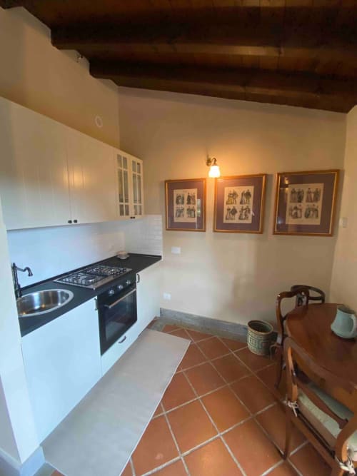 Cucina moderna con mobili bianchi, fornello a gas nero e pavimento in cotto a Castelgandolfo, vicino Porto Cervo