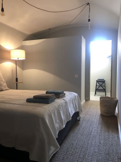Chambre moderne de la villa La Conciergerie du Cap Corse à Centuri avec lit, lampe et salle de bain attenante