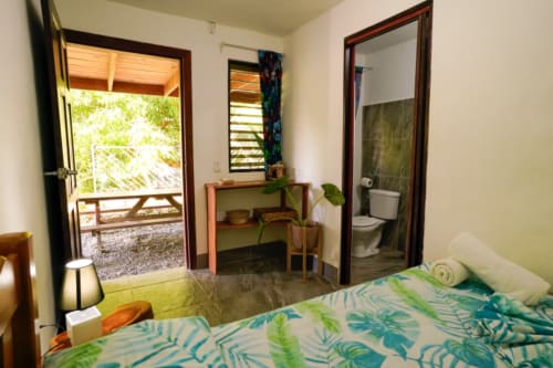 Habitación Hotel Swell Pavones con 2 dormitorios, ropa de cama tropical, baño privado y patio con vistas a Pavones, Costa Rica