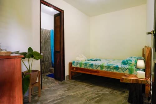 Habitación con 2 camas de Hotel Swell Pavones, cama de madera, ropa de cama tropical, plantas en maceta y mobiliario sencillo en Pavones, Costa Rica