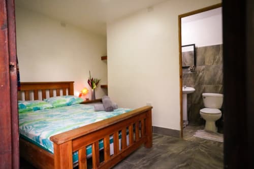 Habitación 3 del Hotel Swell Pavones con cama de madera y baño privado con inodoro y ducha en Pavones, Costa Rica