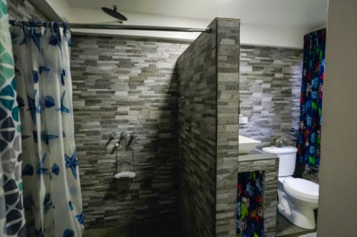 Baño moderno en la Habitación 6 del Hotel Swell Pavones con azulejos grises, ducha y inodoro en Pavones, CR
