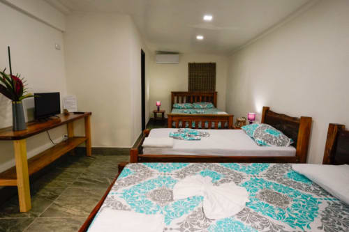 Habitación 7 del Hotel Swell Pavones con dos camas de madera, ropa de cama turquesa estampada, escritorio con TV y comodidades modernas en Pavones, CR