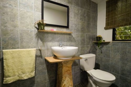 Baño moderno del Hotel Swell Pavones en Pavones con lavamanos tipo vessel, inodoro y detalles en verde